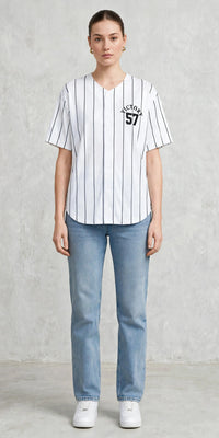 Victory jersey with vertical black stripes, short sleeves, and "Victory 57" logo on the front, worn with light blue jeans and white sneakers.